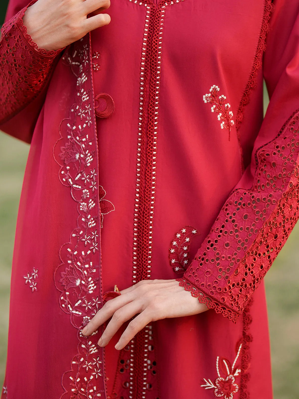 Close-up front and sleeve detail of vibrant red lawn stitched 3-piece suit featuring eyelet cutwork sleeves, central lace stitching, and scalloped embroidered dupatta border from Baad-e-Saba by INEJ.