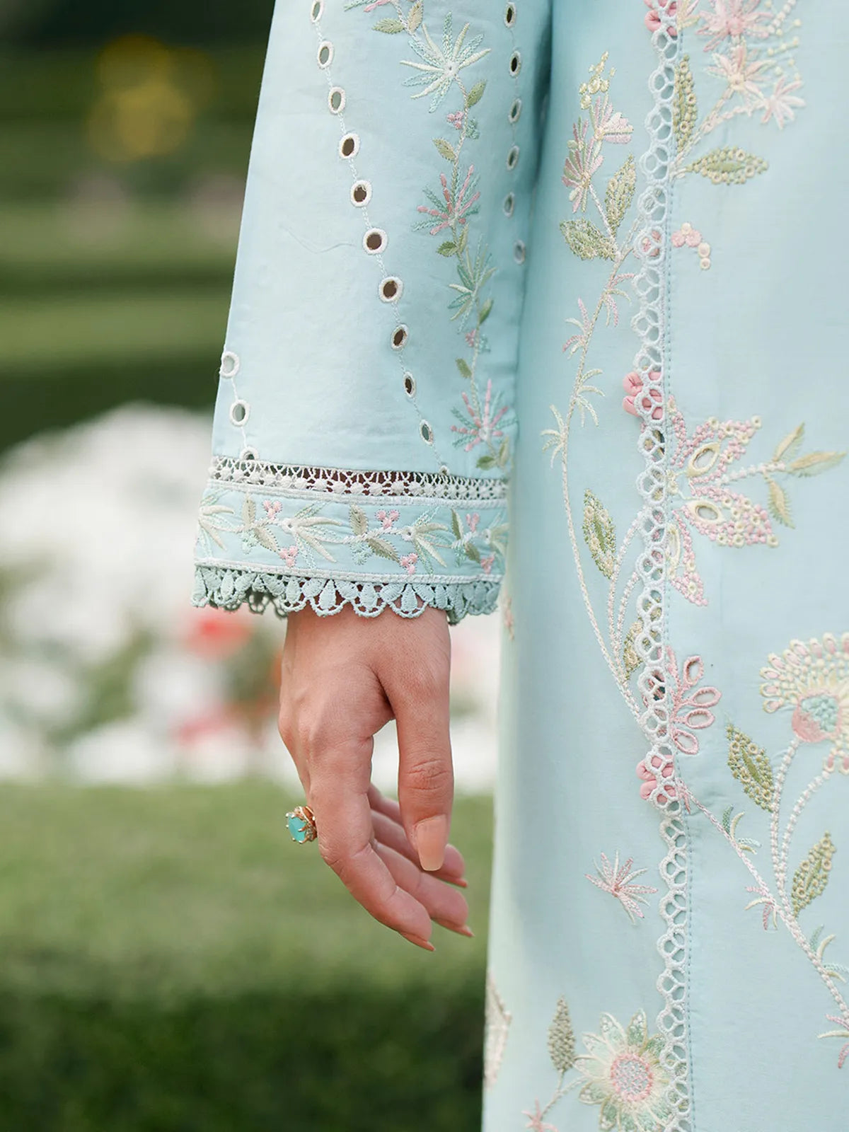 Close-up sleeve and front panel detail of sky blue lawn stitched 3-piece suit featuring delicate pastel floral embroidery and eyelet sleeve trim from Baad-e-Saba by INEJ.