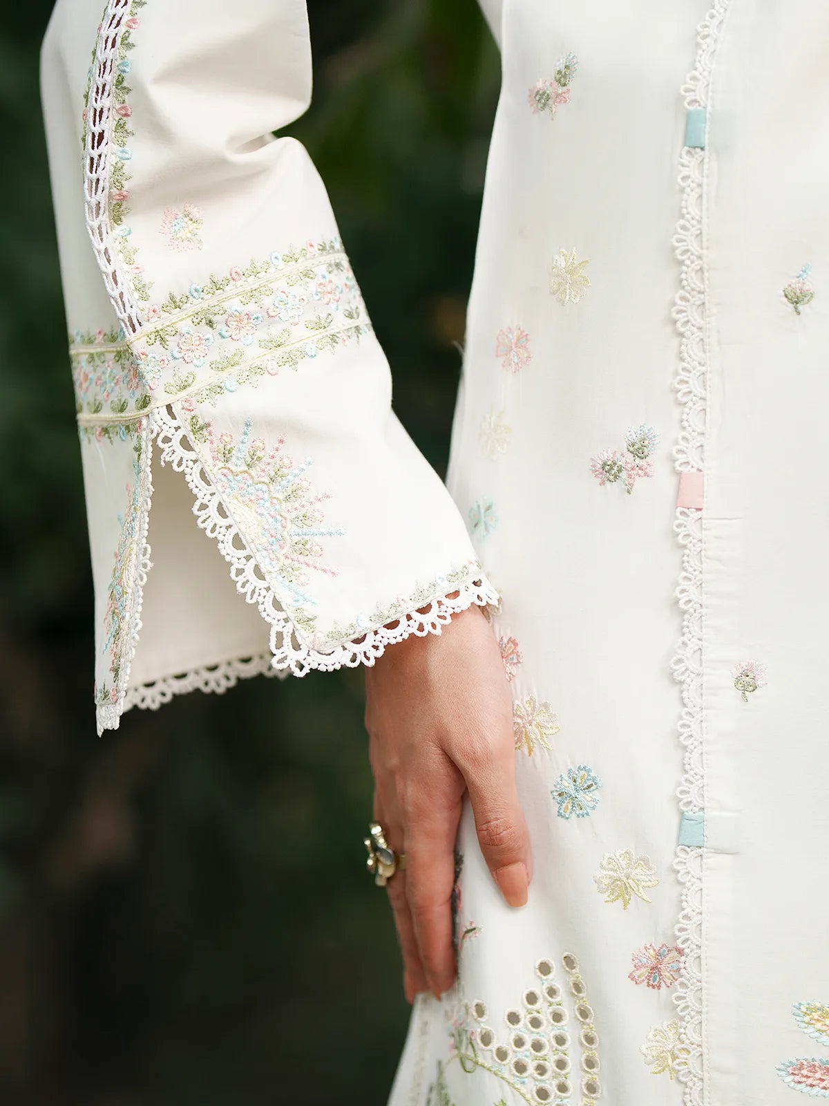 Close-up sleeve cuff and side detail of off-white lawn stitched 3-piece suit featuring a slit cuff with delicate lace edging, pastel thread embroidery, and color-accented loop details from Baad-e-Saba by INEJ.
