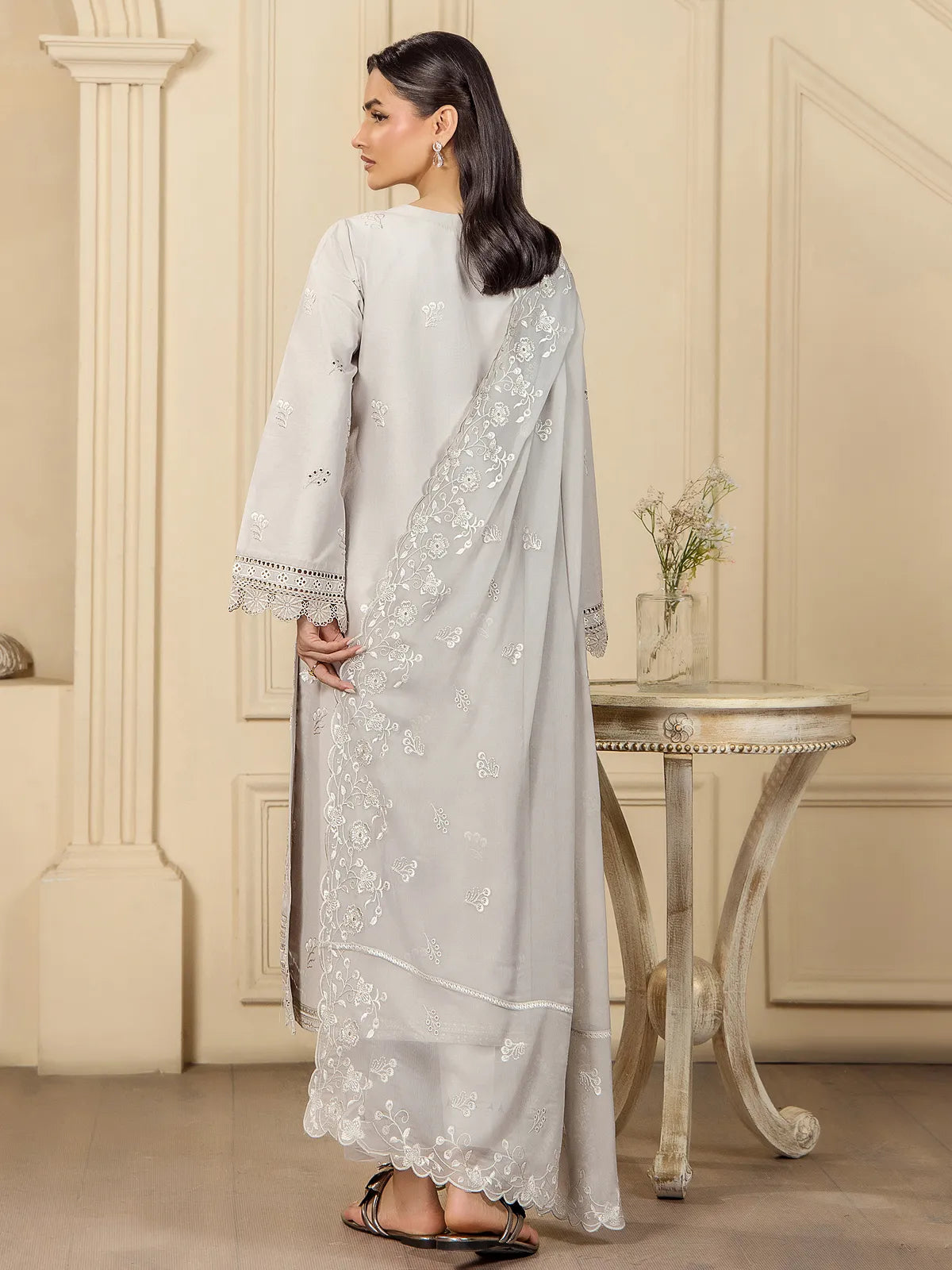 Back view of a model wearing a grey 3-piece embroidered lawn suit showing the floral embroidered dupatta drape by INEJ.