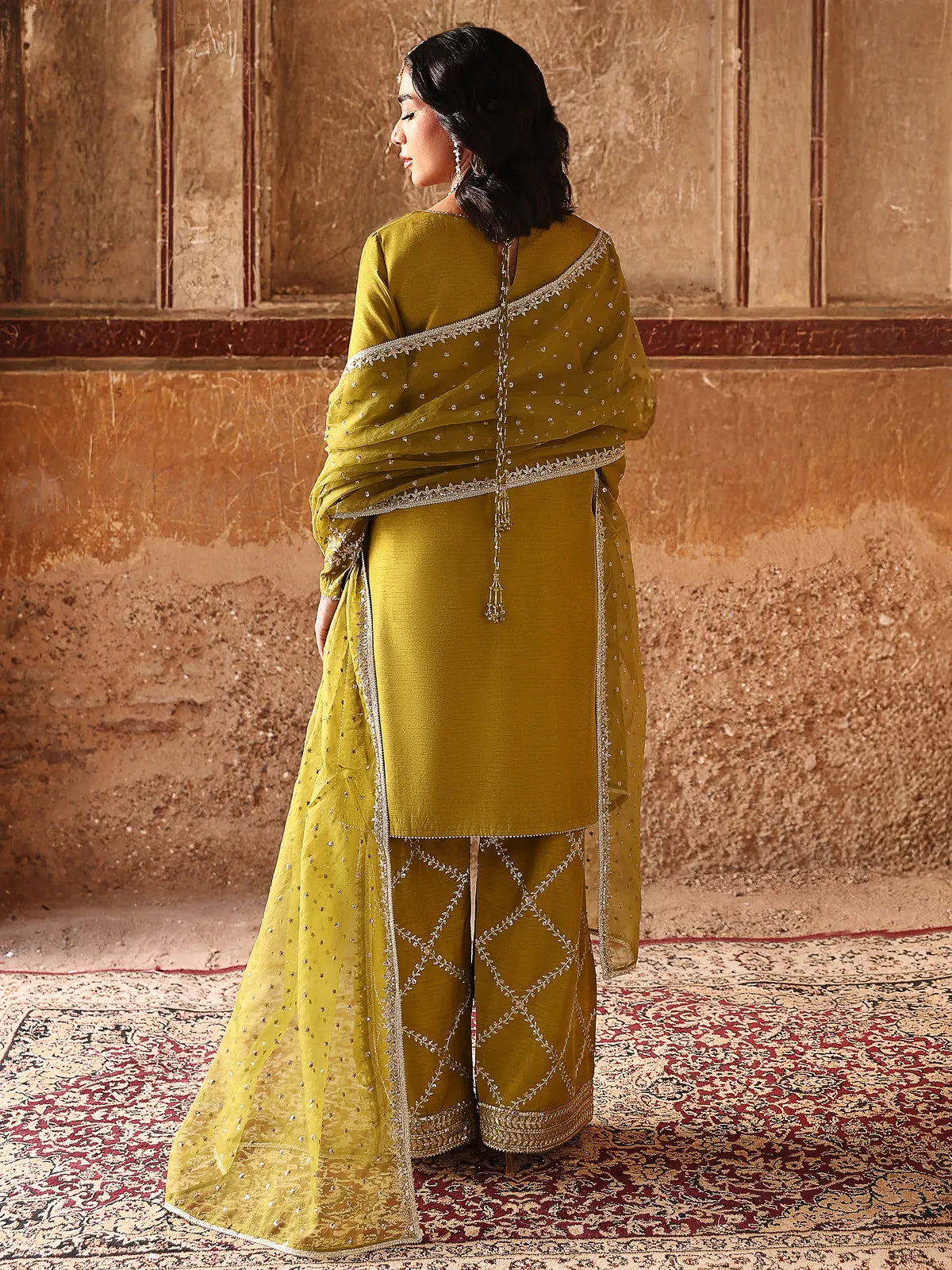Back full-length view of olive green stitched 3-piece luxury silk suit with long neck tassels from Khat by INEJ.