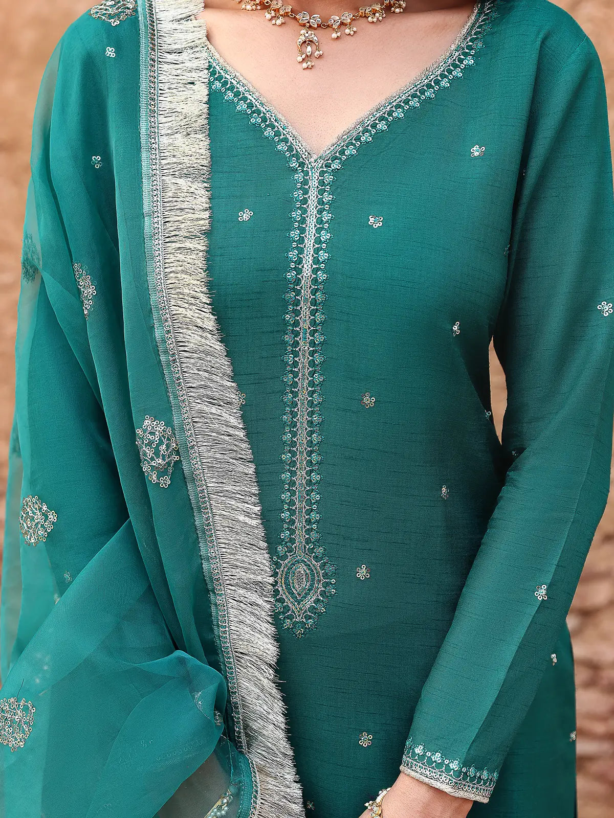 Close-up view of embroidered v-neckline and fringe border dupatta on teal silk suit from Khat by INEJ.