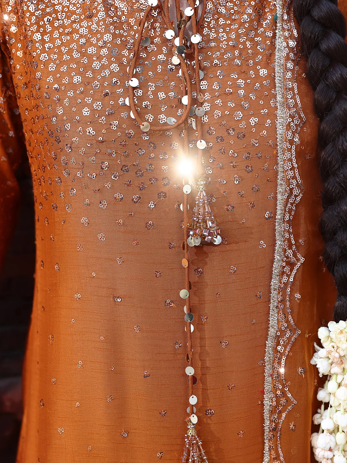 Close-up view of embellished neckline with tassel tie-up details on rust luxury silk suit from Khat by INEJ.