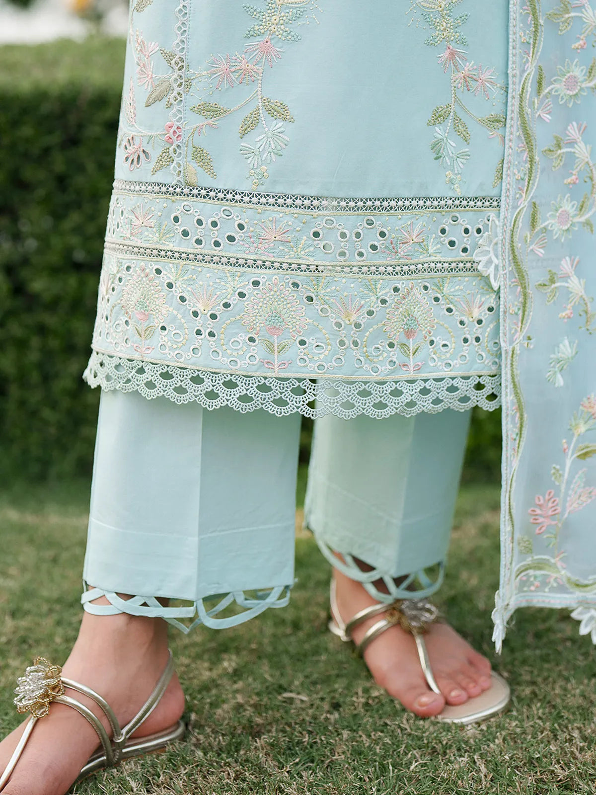 Close-up hem and trouser detail of sky blue lawn stitched 3-piece suit featuring multi-tier cutwork daman border and scalloped trouser cuffs from Baad-e-Saba by INEJ.