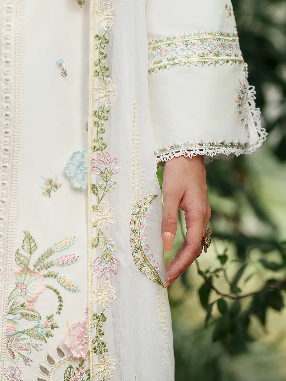 Close-up front and sleeve detail of off-white lawn stitched 3-piece suit featuring pastel floral embroidery, lace panel inserts, lace-trimmed sleeve cuffs, and floral embroidered dupatta border from Baad-e-Saba by INEJ.