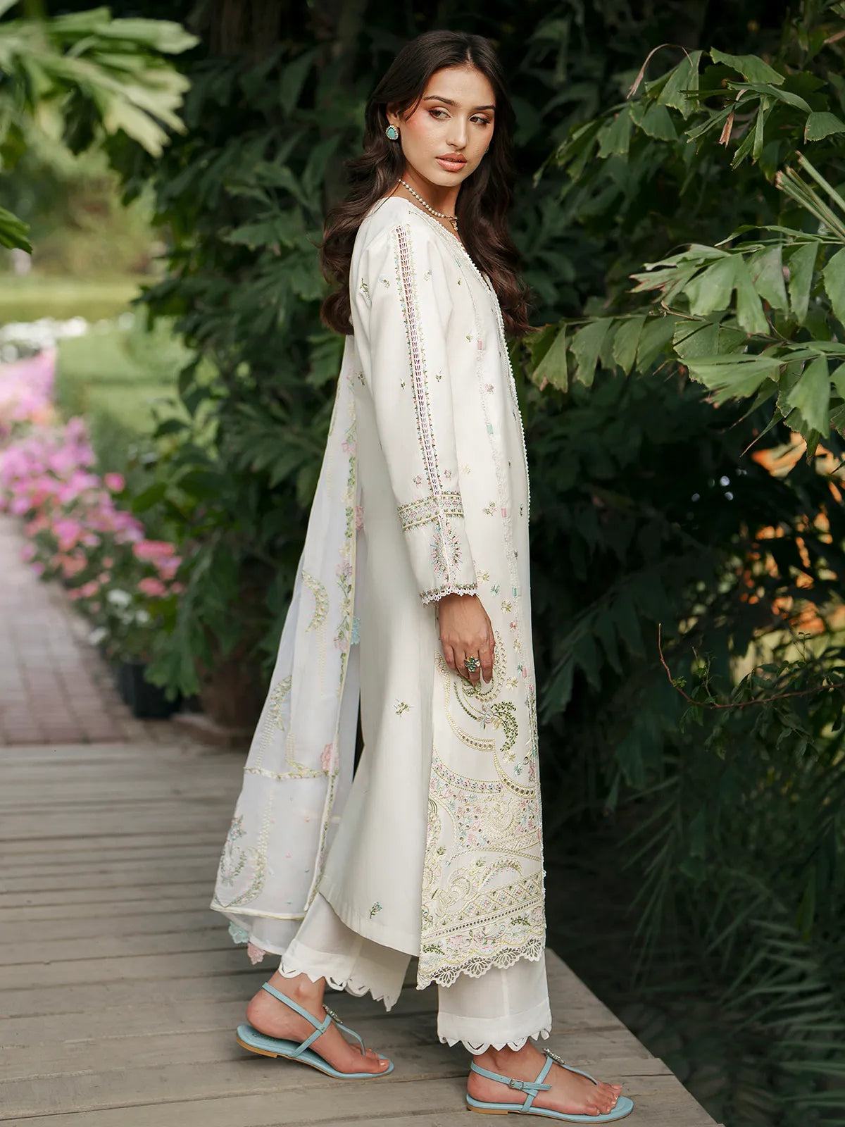 Side full-length view of off-white lawn stitched 3-piece suit featuring pastel floral embroidery on daman, scalloped cutwork borders, and matching embroidered dupatta from Baad-e-Saba by INEJ.