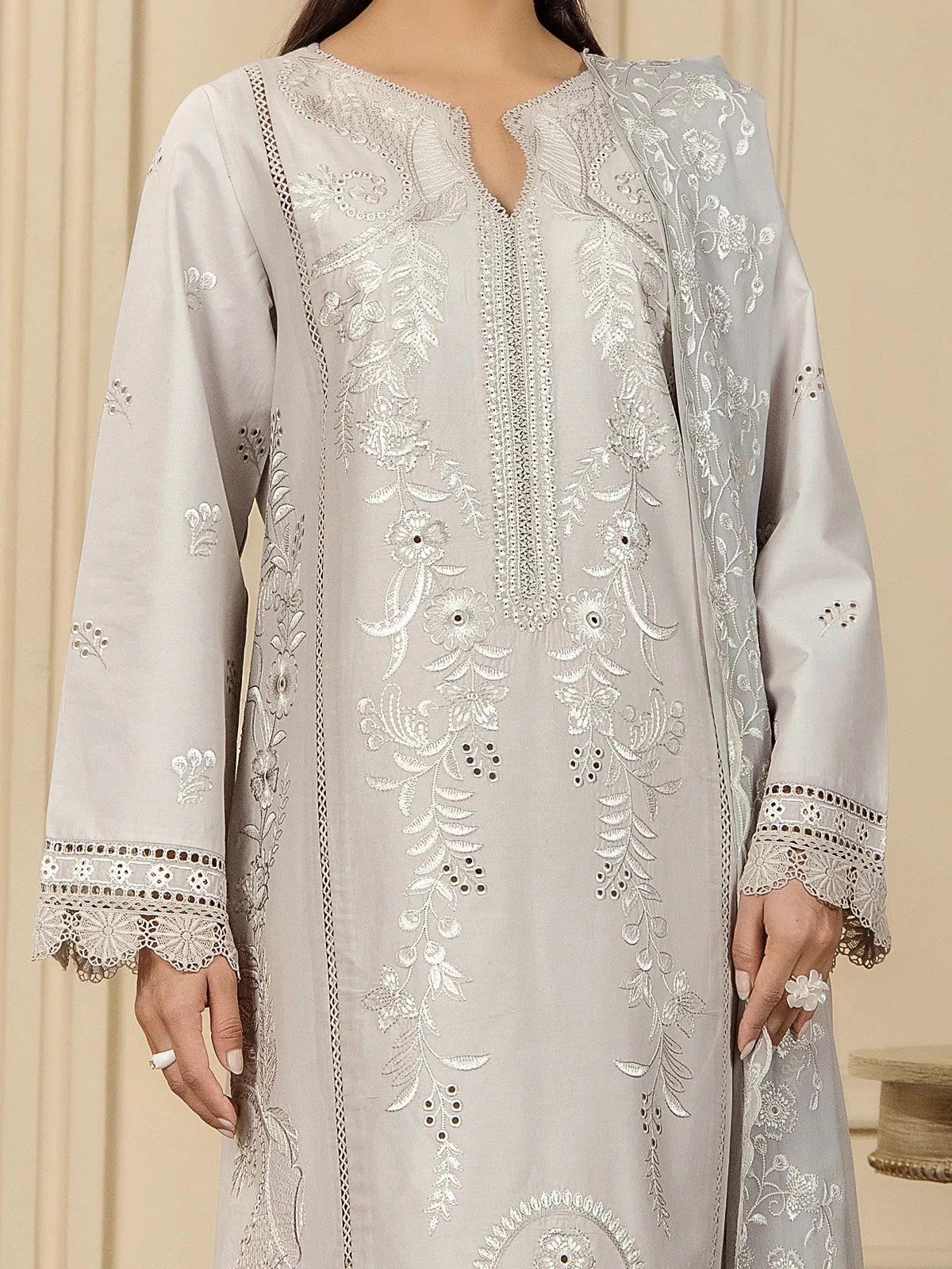 Close-up view of intricate white floral embroidery, schiffli cutwork, and lace sleeve borders on the grey lawn shirt by INEJ.