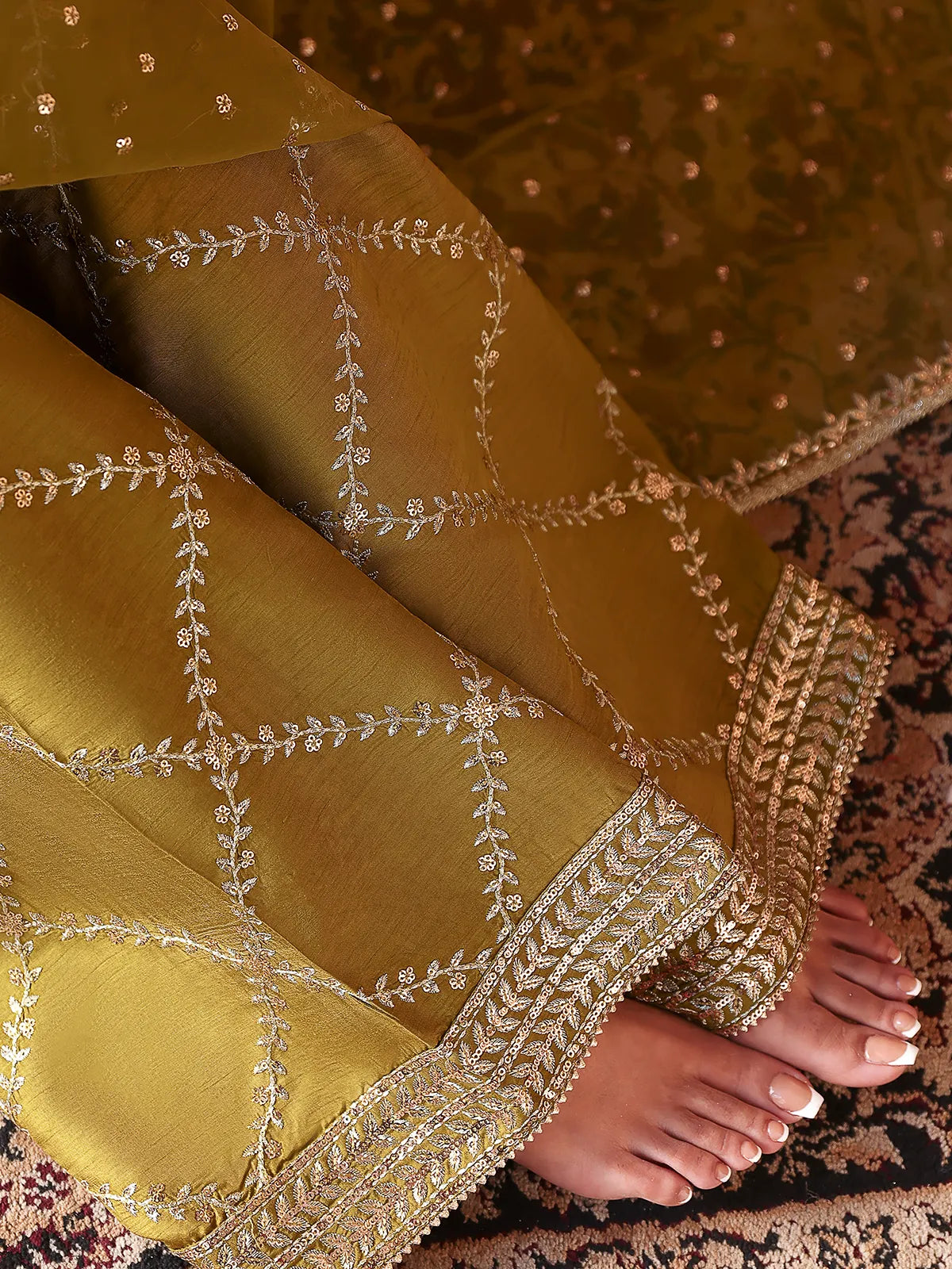 Close-up view of silver leaf lattice embroidered trouser hem on olive green silk suit from Khat by INEJ.