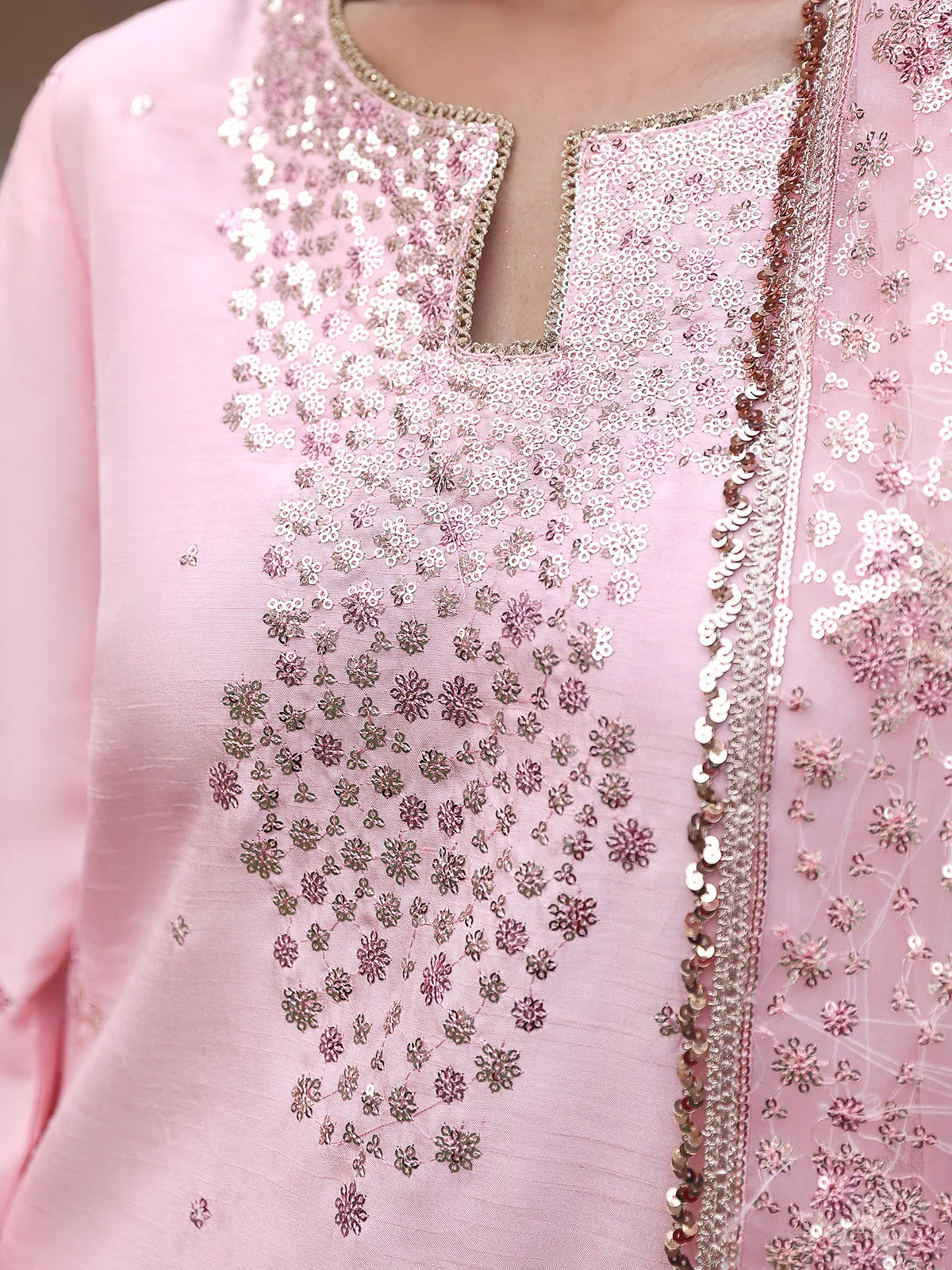 Close-up view of keyhole neckline and floral sequin embroidery spray on pink silk shirt from Khat by INEJ.
