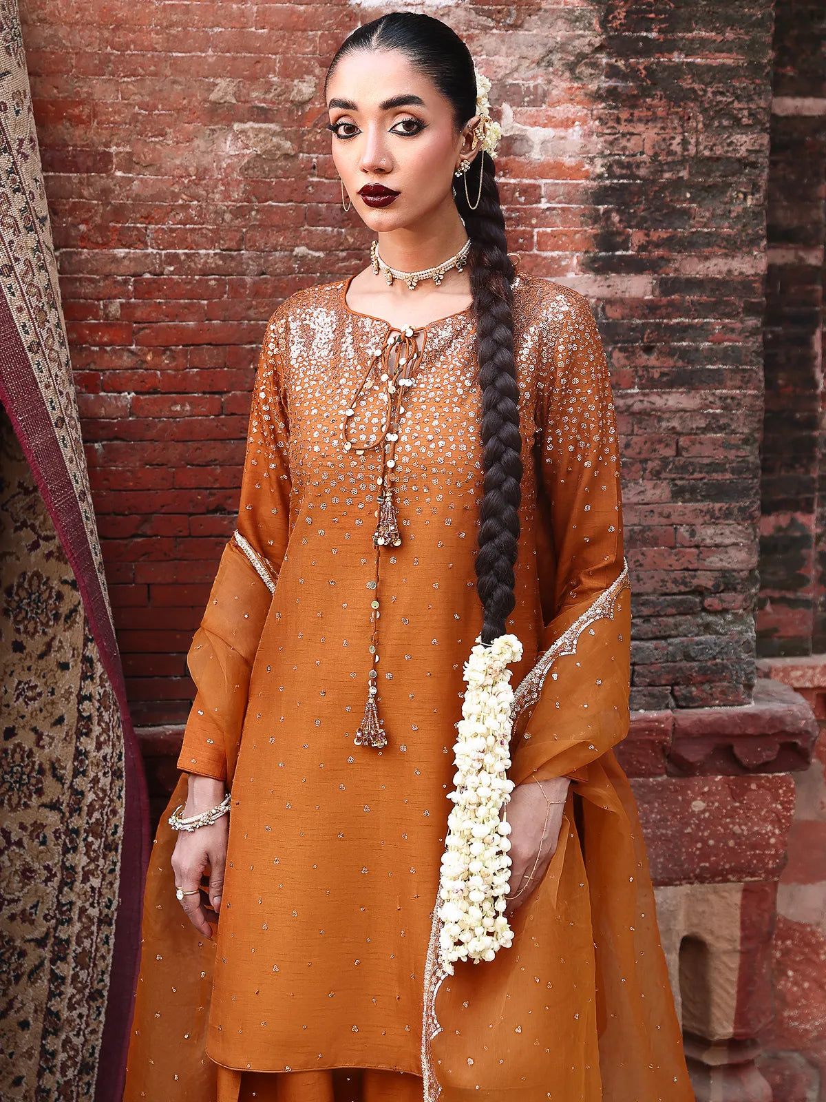 Close-up view of embellished neckline with tassel tie-up details on rust luxury silk suit from Khat by INEJ.