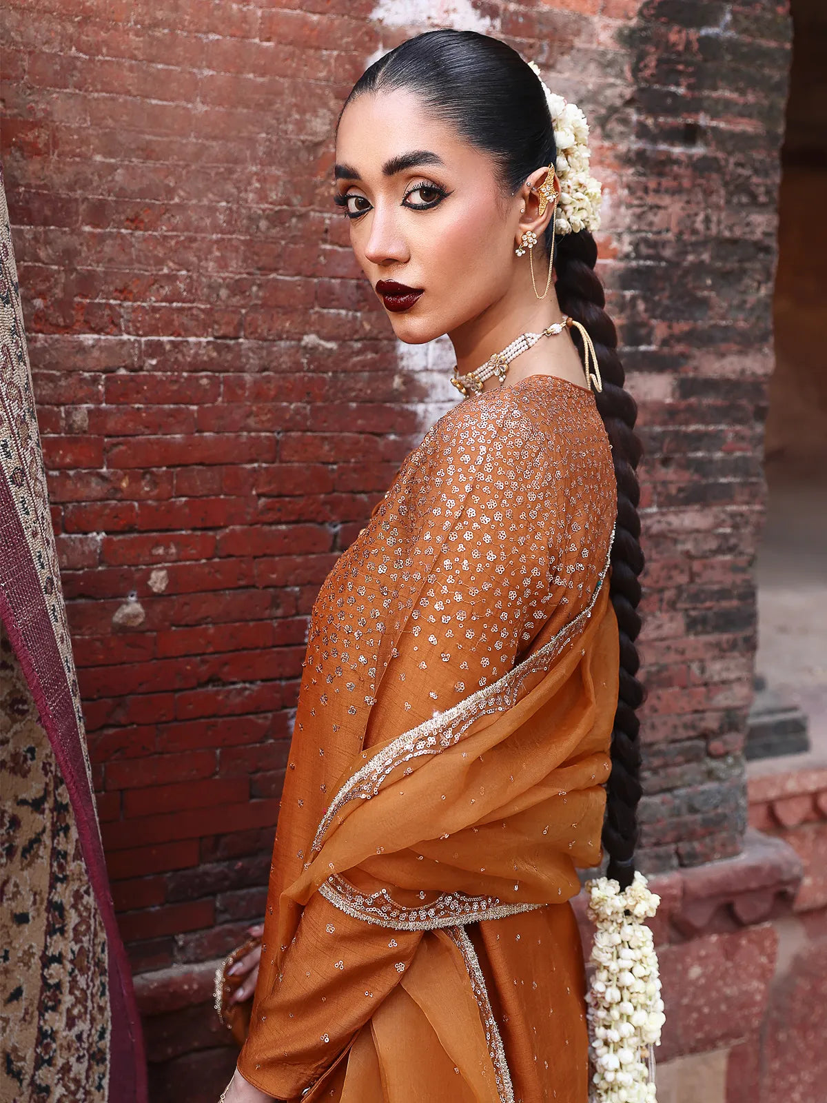 Side angle view of rust rust-orange embellished stitched luxury silk suit with draped dupatta from Khat by INEJ.