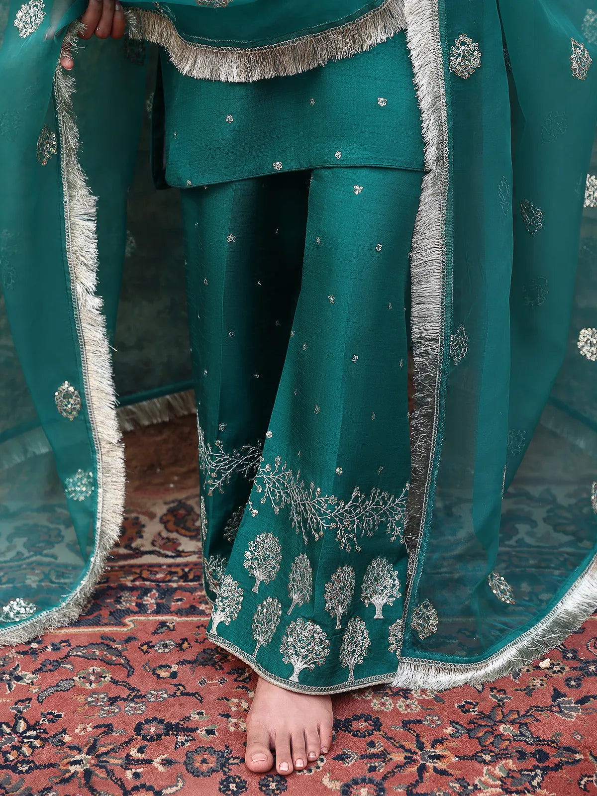 Close-up view of embroidered trouser hemline and fringe lace dupatta border on teal luxury silk from Khat suit by INEJ.