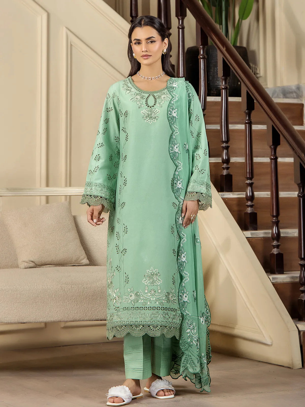 Full front view of a model wearing a mint green 3-piece embroidered lawn suit with matching scalloped dupatta and lace-trimmed trousers by INEJ.