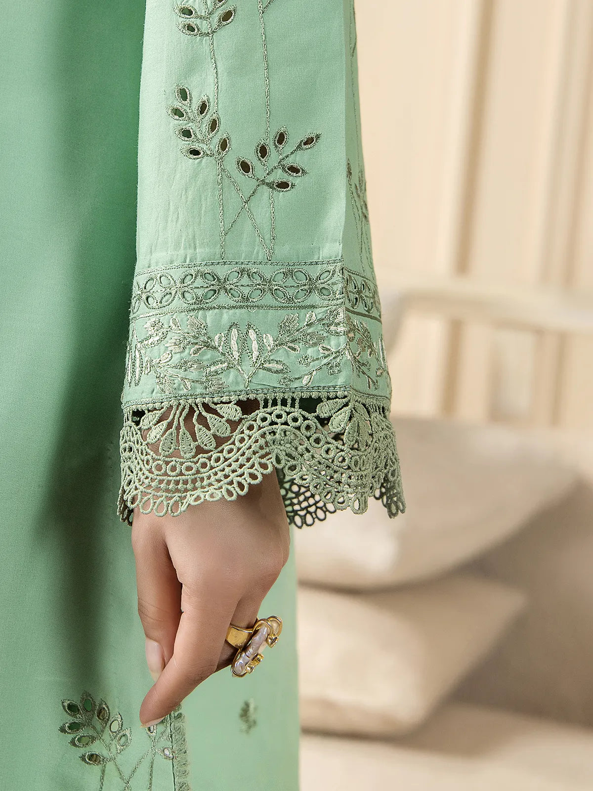 Detailed close-up of leaf schiffli cutwork embroidery and ornate lace trim edging on the sleeves of the mint green suit by INEJ.