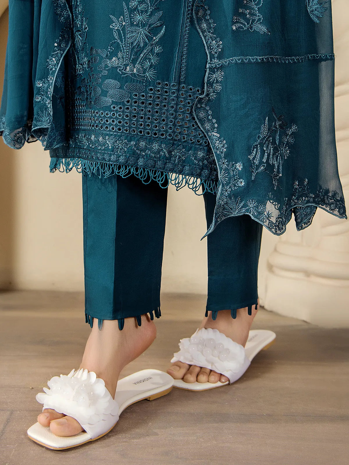 Detailed close-up of loop trim trouser hems, embroidered shirt daman border, and scalloped dupatta edges on the teal blue suit by INEJ