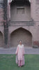 Video reel showing a model walking through a historic courtyard wearing the Gulabiya soft pink embroidered suit from the Khat collection by INEJ.