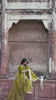 Video reel of a model sitting on a stone pedestal with gajra flowers wearing the Zardum olive green embroidered suit from the Khat collection by INEJ.