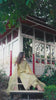 Video reel of a model sitting on wooden pavilion steps wearing an olive green 3-piece embroidered suit from the Bad-e-Saba collection by INEJ.